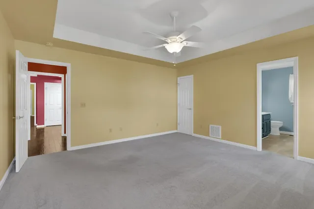 a view of an empty room with chandelier fan