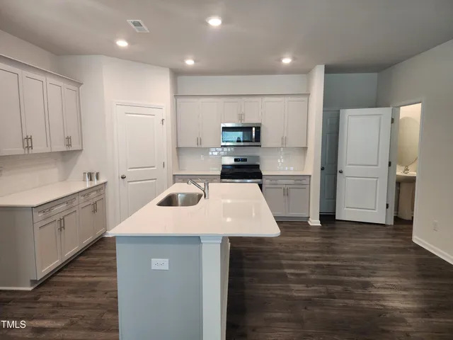 a kitchen with a sink a stove a refrigerator and cabinets