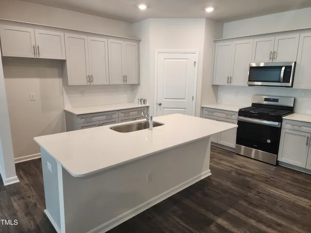 a kitchen with stainless steel appliances a sink a stove a microwave and cabinets