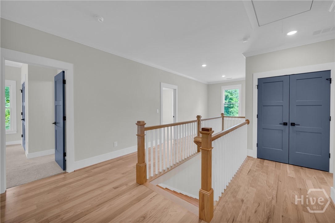 2476 St Martin Way Monroe, GA 30656 - Photo 31 of 75 Upper-level hallway featuring wood-finish flooring, white baluster railing with wood newel posts, recessed lighting, and panel doors with dark hardware