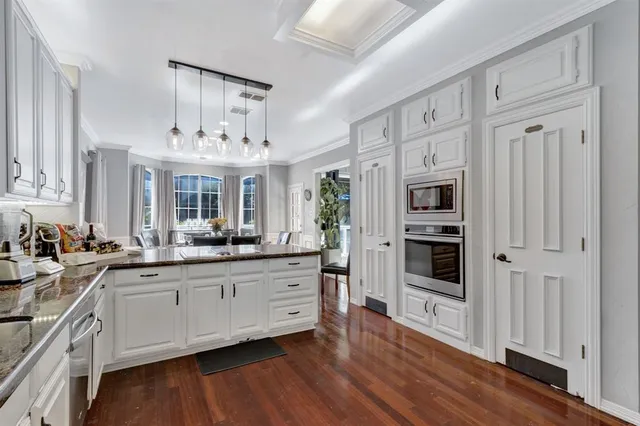 a kitchen with stainless steel appliances a sink stove and wooden floor