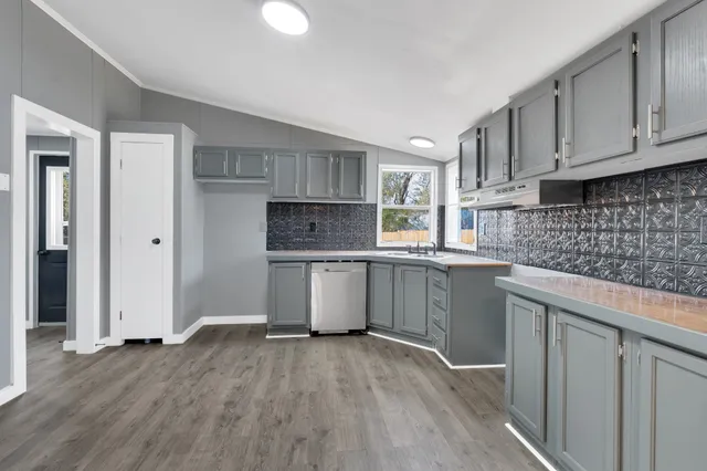 a kitchen with kitchen island granite countertop a sink cabinets and stainless steel appliances
