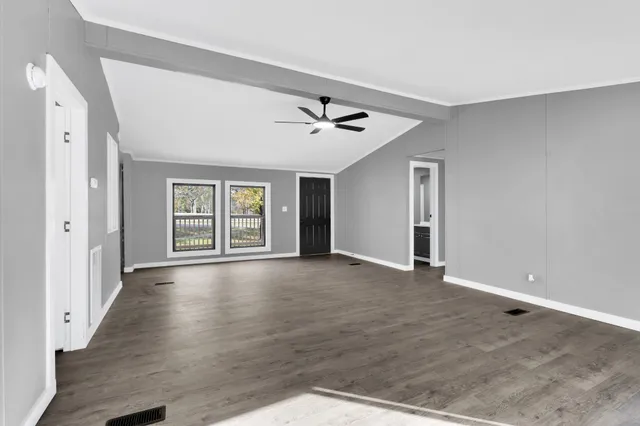 a view of an empty room with a window and wooden floor