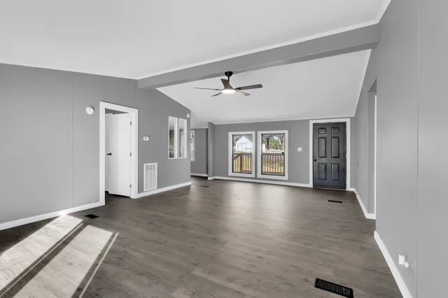 a view of an empty room with window and wooden floor