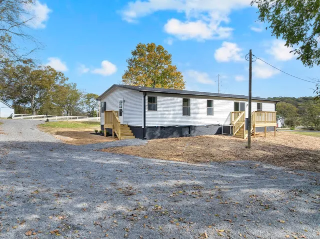 a view of a house with backyard and a tree
