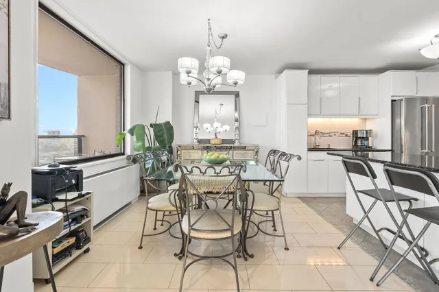 a view of a dining room with furniture a chandelier and large windows