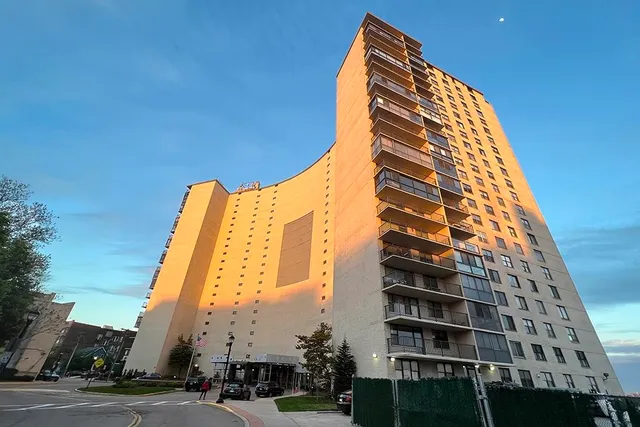 a large hall with stainless steel appliances kitchen island granite countertop a refrigerator and a sink