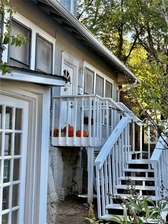 a view of a house with wooden stairs stairs and a large tree