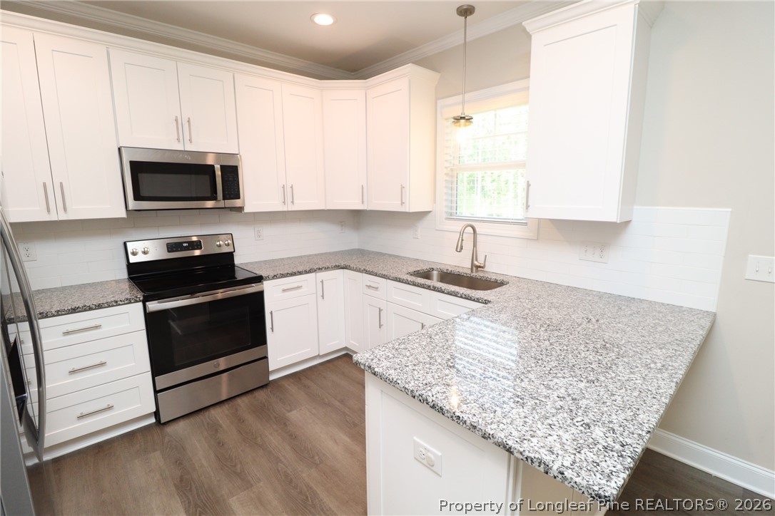 8424 Rhodes Road Apex, NC 27539 - Photo 9 of 31 a kitchen with granite countertop white cabinets and a stove