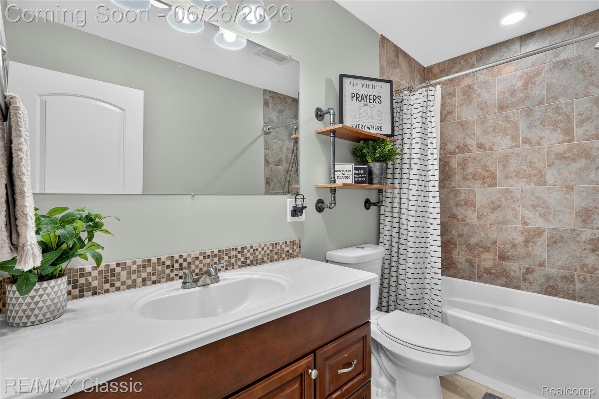 3205 North Milford Road Highland, MI 48357 - Photo 25 of 53 Bathroom featuring a wood-finish vanity with an integrated sink, a mosaic tile backsplash, and a tiled tub/shower combination
