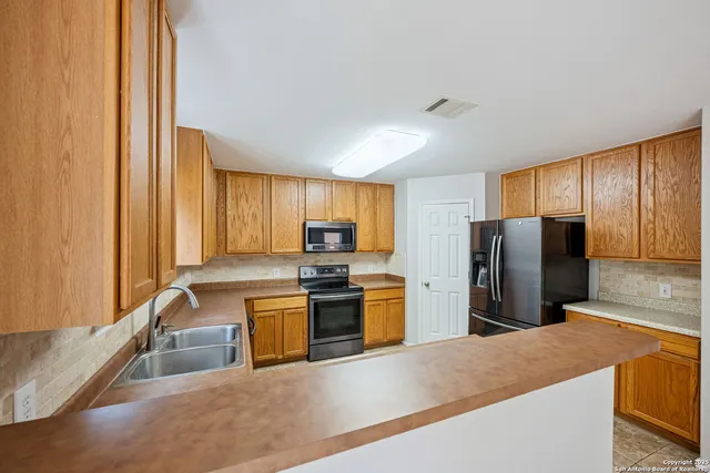 a kitchen with stainless steel appliances granite countertop a refrigerator a stove and a sink with wooden cabinets