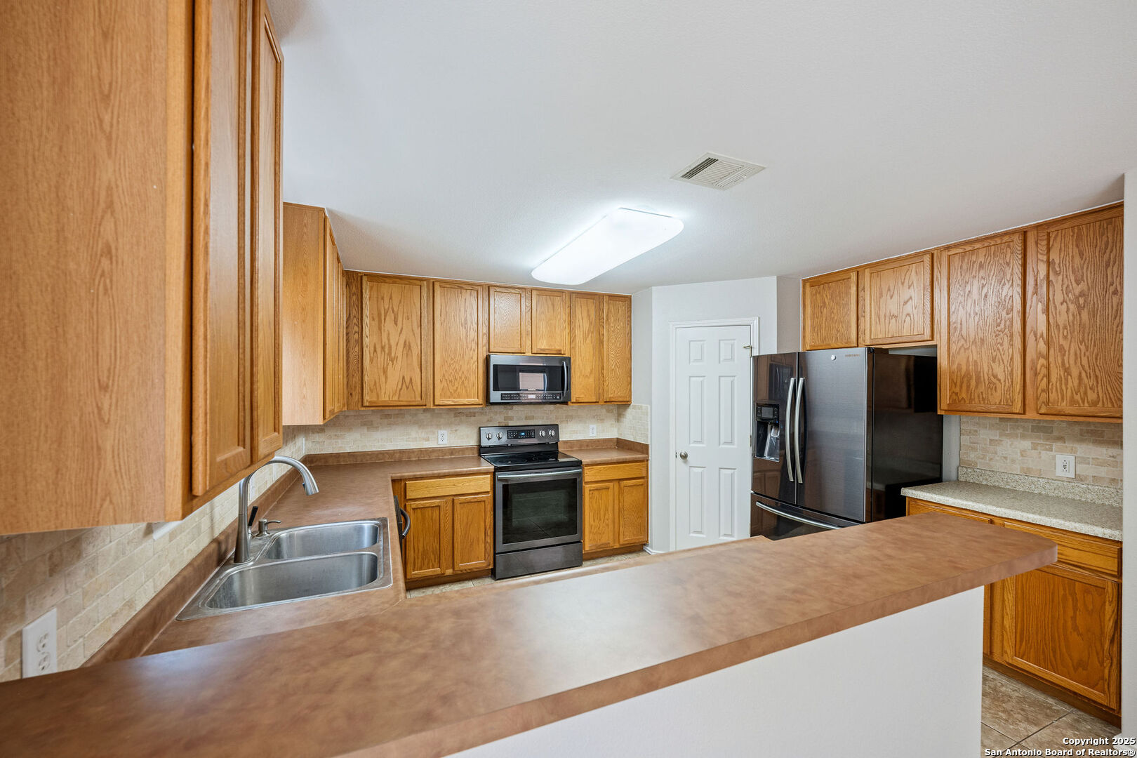 4030 Bear Oak Path San Antonio, TX 78223 - Photo 11 of 31 a kitchen with stainless steel appliances granite countertop a refrigerator a stove and a sink with wooden cabinets