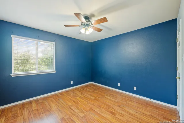 an empty room with windows and fan