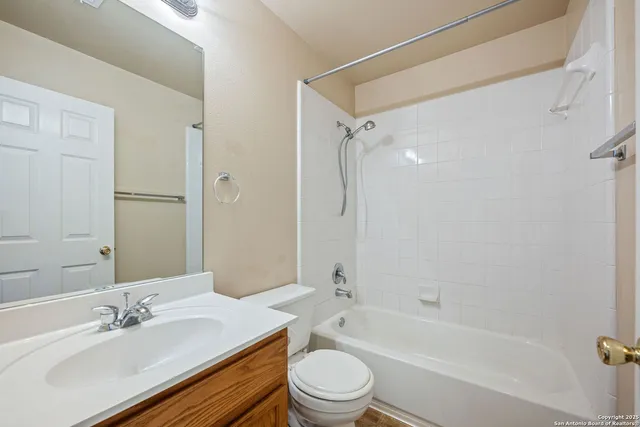 a bathroom with a bathtub shower sink vanity mirror and toilet
