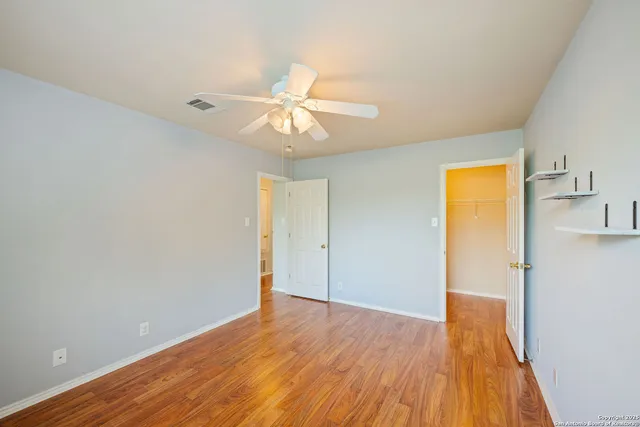 a view of empty room with wooden floor and fan