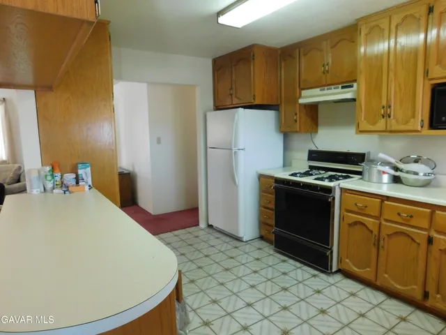 a kitchen with granite countertop a sink a stove a refrigerator and wooden cabinets