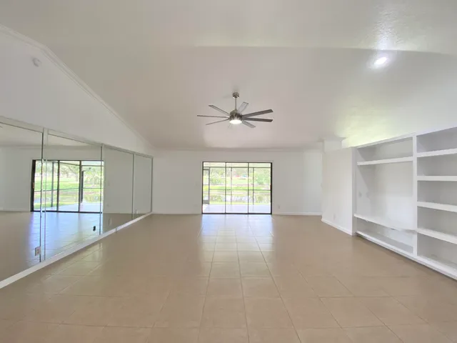 an empty room with windows and ceiling fan