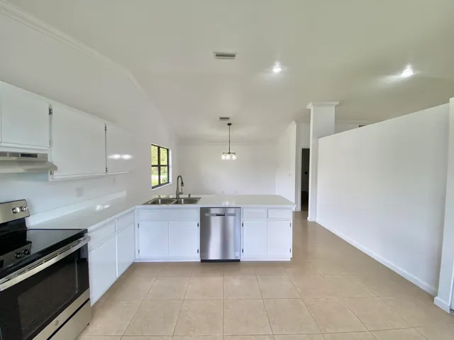 a large kitchen with granite countertop a sink and white cabinets