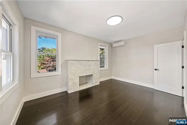 an empty room with wooden floor cabinet and windows