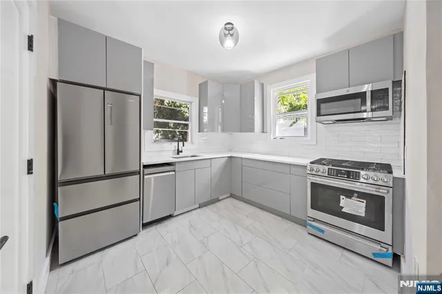 a kitchen with stainless steel appliances a refrigerator sink and microwave