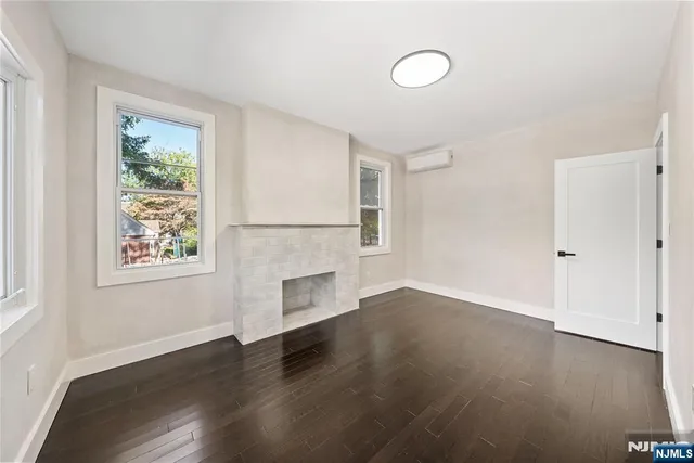an empty room with wooden floor cabinet and windows