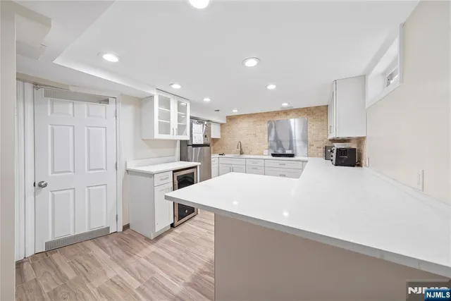 a large white kitchen with kitchen island a sink a stove a refrigerator and white cabinets