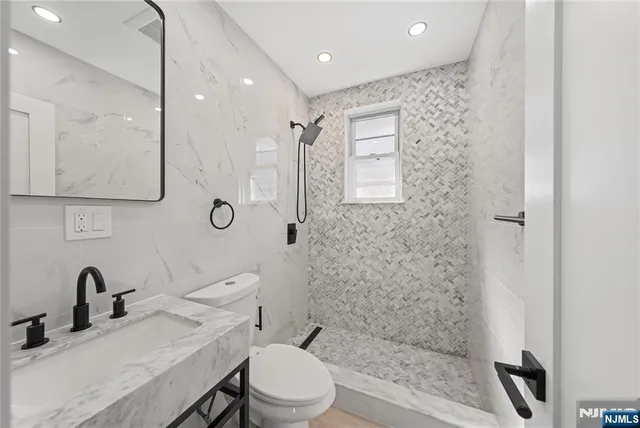 a bathroom with a toilet a sink a mirror and shower