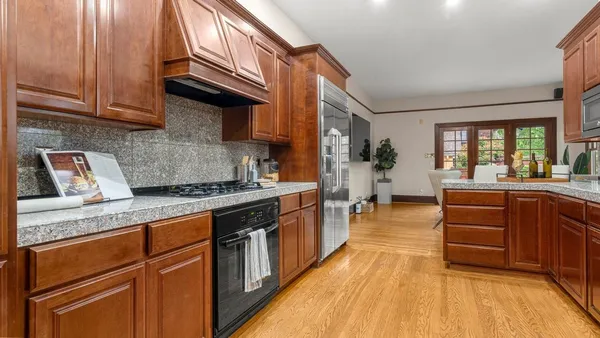 a kitchen with stainless steel appliances granite countertop a stove a sink dishwasher and cabinets with wooden floor