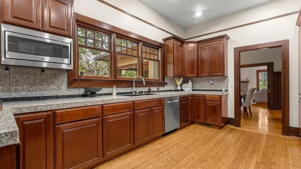 a kitchen with stainless steel appliances granite countertop wooden cabinets a sink and dishwasher a stove with wooden floor