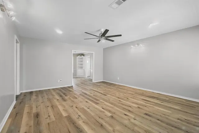 an empty room with wooden floor and ceiling fan