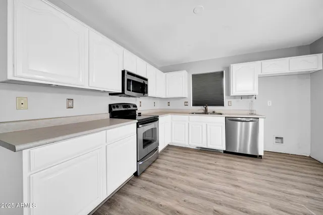 a kitchen with a wooden floor a refrigerator and a stove top oven
