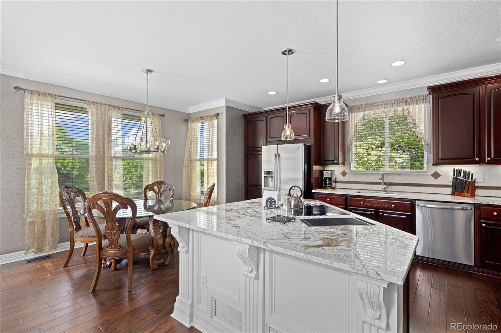 6374 Umber Circle Arvada, CO 80403 - Photo 11 of 33 a kitchen with stainless steel appliances granite countertop a stove a sink a microwave a dining table and chairs