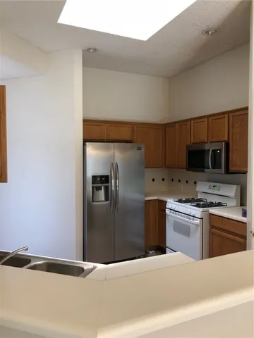 a kitchen with stainless steel appliances granite countertop a refrigerator a stove and a sink with wooden floor