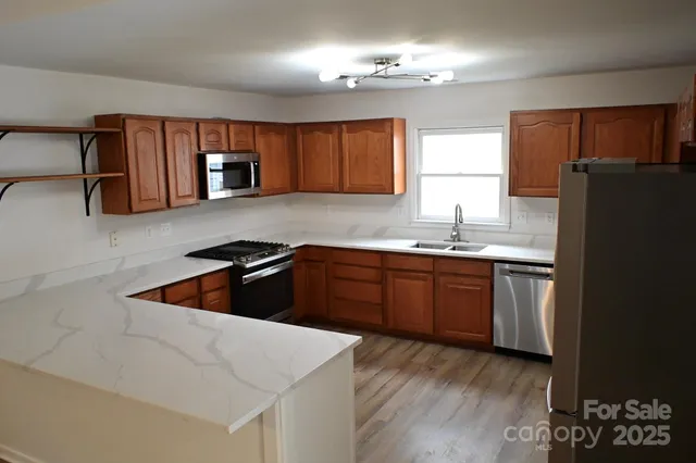 a kitchen with stainless steel appliances kitchen island a sink dishwasher a refrigerator and cabinets with wooden floor