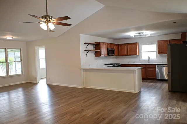 a kitchen with stainless steel appliances granite countertop a refrigerator a stove a sink dishwasher and a oven with wooden floor