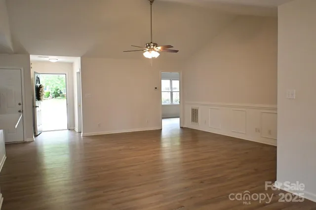a view of an empty room with window and wooden floor