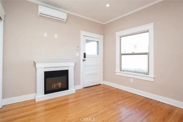 an empty room with wooden floor fireplace and windows