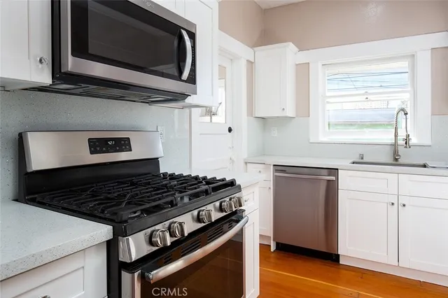 a kitchen with stainless steel appliances a stove a microwave a sink and cabinets