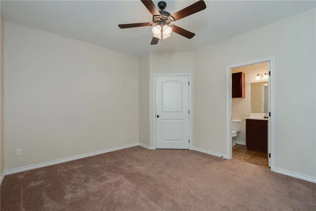 an empty room with closet and a ceiling fan