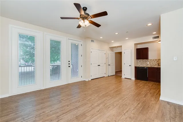 a view of an empty room with kitchen and a window