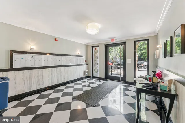 a living room with a black white checkered floor with a gaming machine and dining chairs