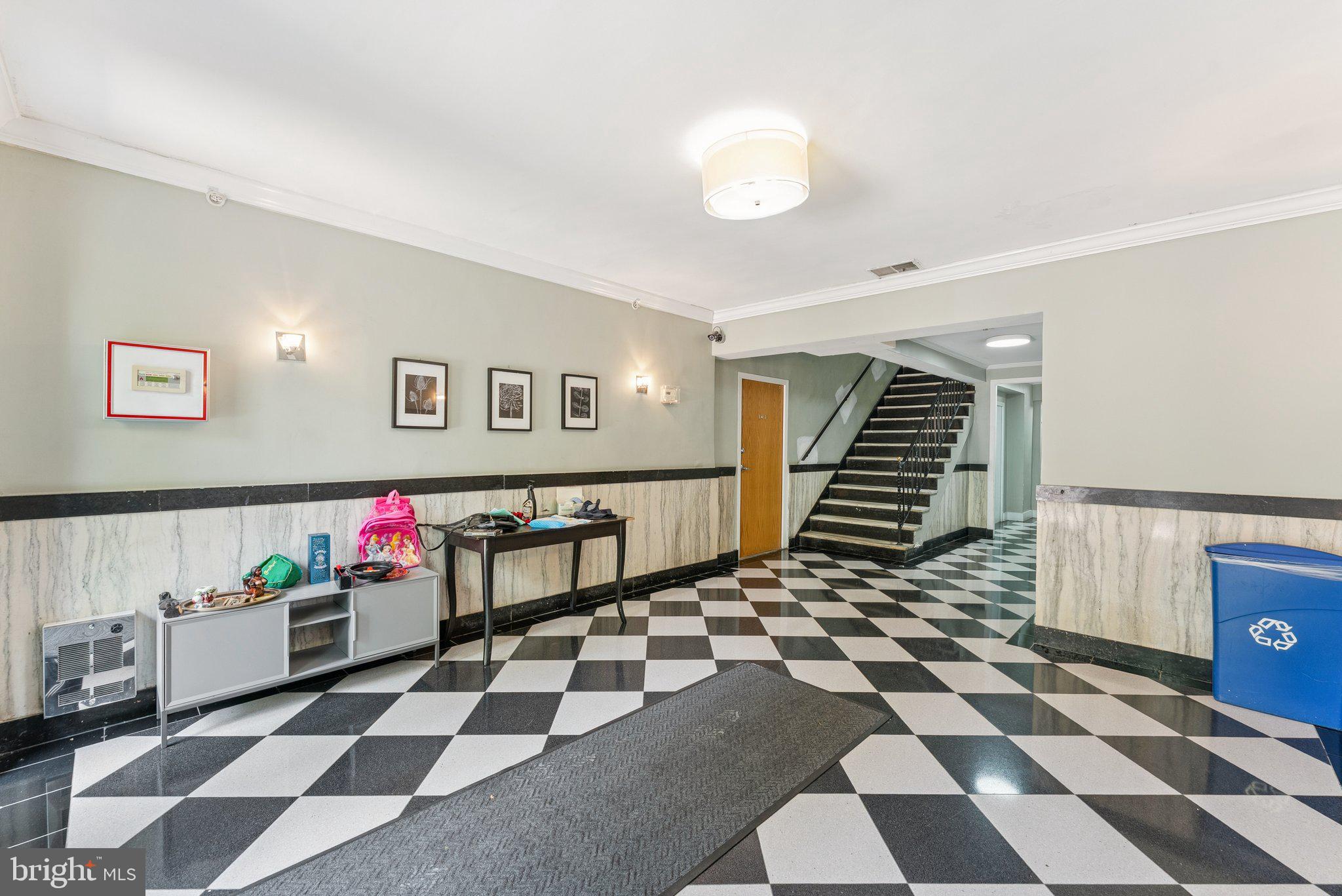 1440 Columbia Road Northwest, Unit 204 Washington, DC 20009 - Photo 21 of 23 a living room with a black white checkered floor with a gaming machine and dining chairs