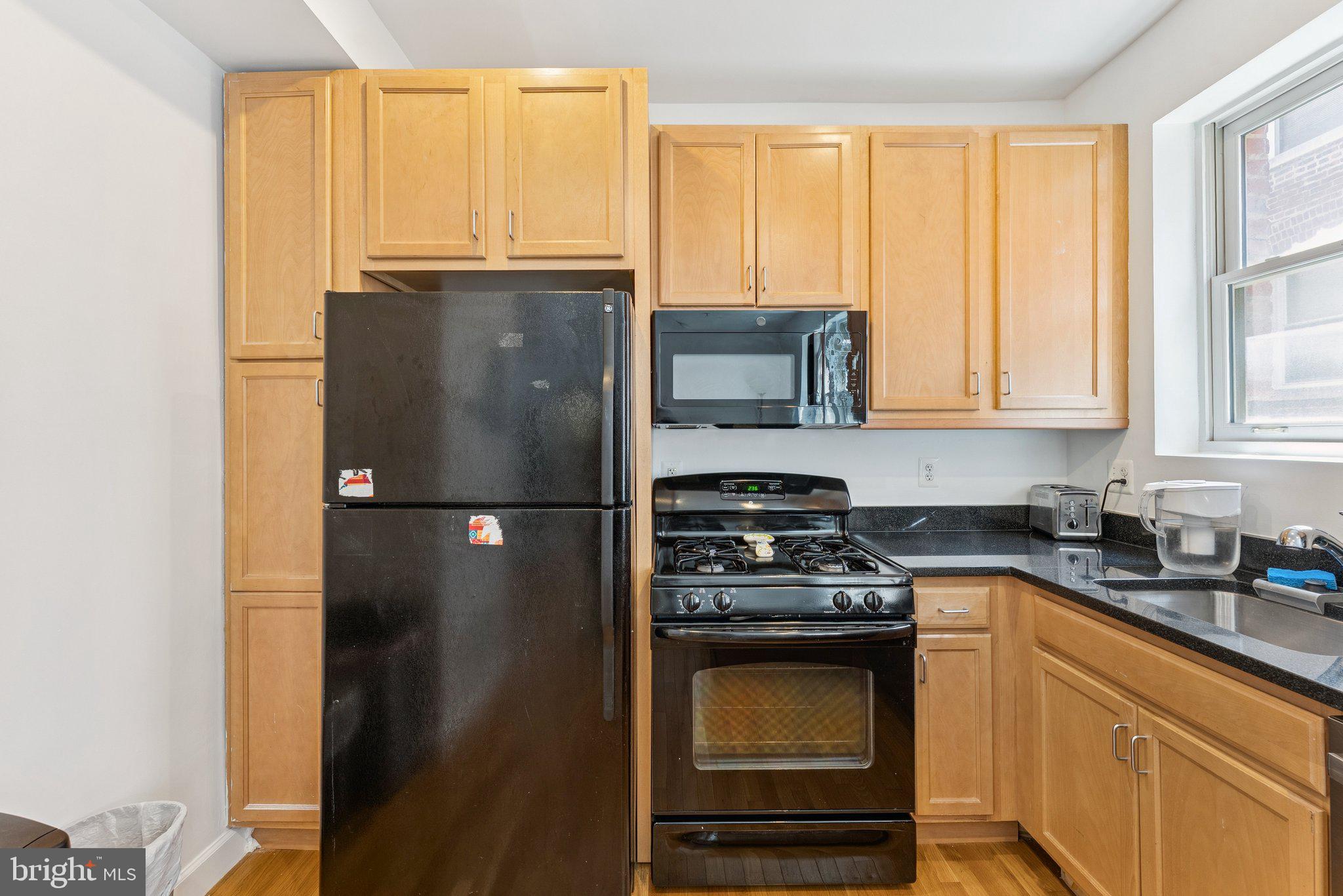 1440 Columbia Road Northwest, Unit 204 Washington, DC 20009 - Photo 8 of 23 a kitchen with granite countertop a refrigerator a stove a sink and a window