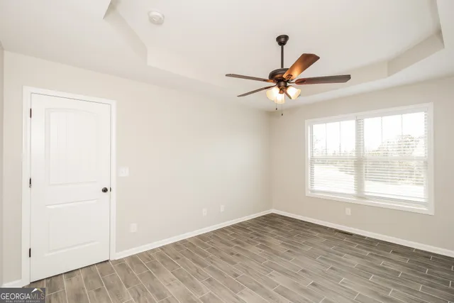a view of an empty room with a window and wooden floor