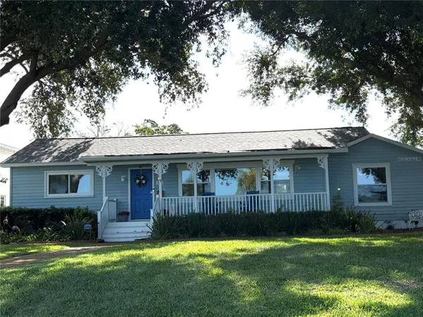 a view of a house with a yard plants and large tree
