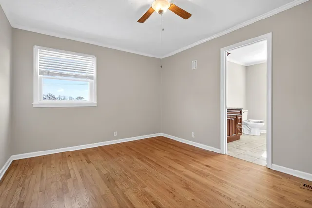 an empty room with wooden floor a ceiling fan and windows