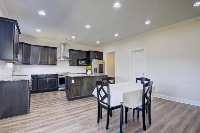 a kitchen with stainless steel appliances granite countertop a kitchen island hardwood floor sink and stove