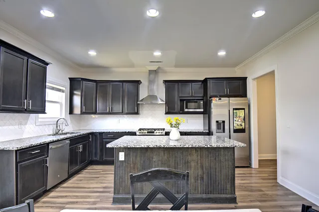 a kitchen with granite countertop a sink a stove a refrigerator cabinets and wooden floor