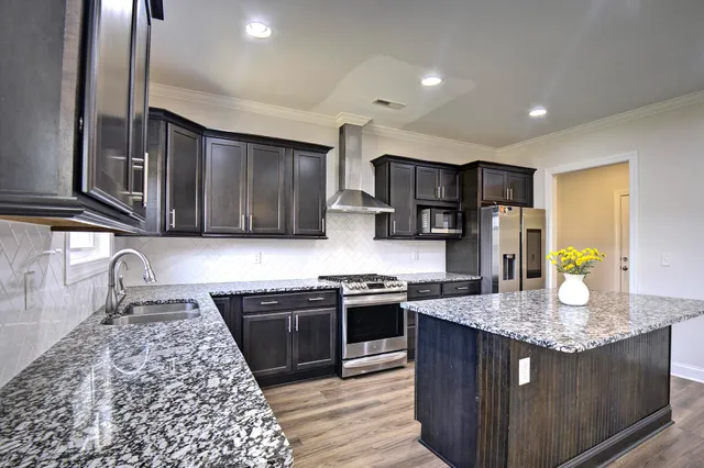 a kitchen with stainless steel appliances granite countertop a sink stove and refrigerator