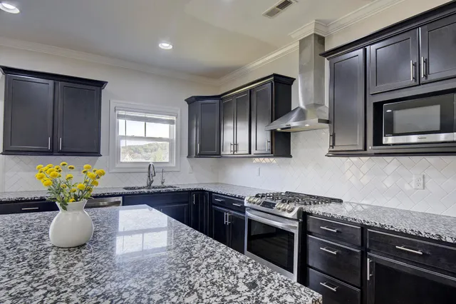 a kitchen with stainless steel appliances granite countertop a sink a stove a microwave cabinets and a dining table